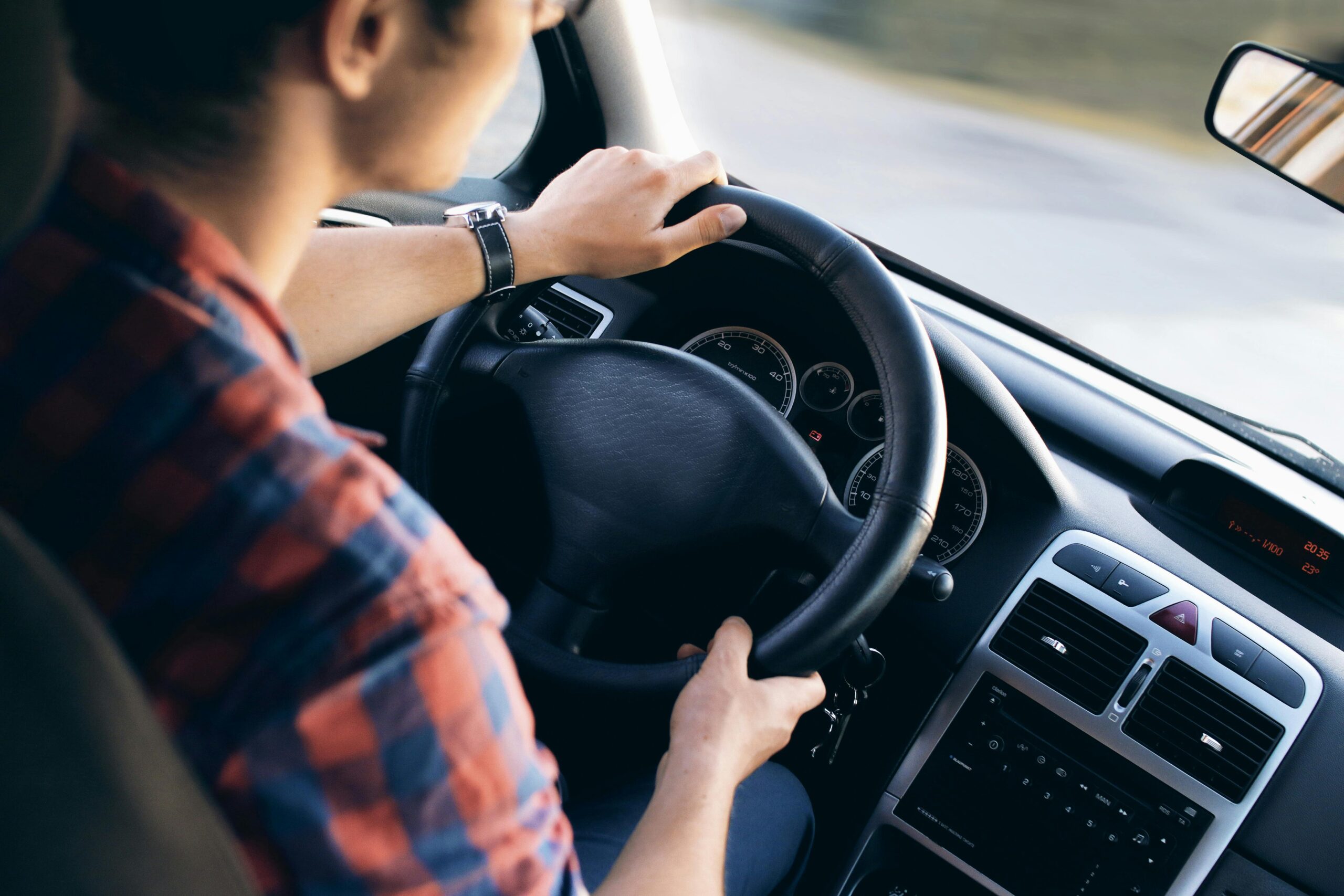 Home Close-up view of a man driving a modern car, showing dashboard and steering details.